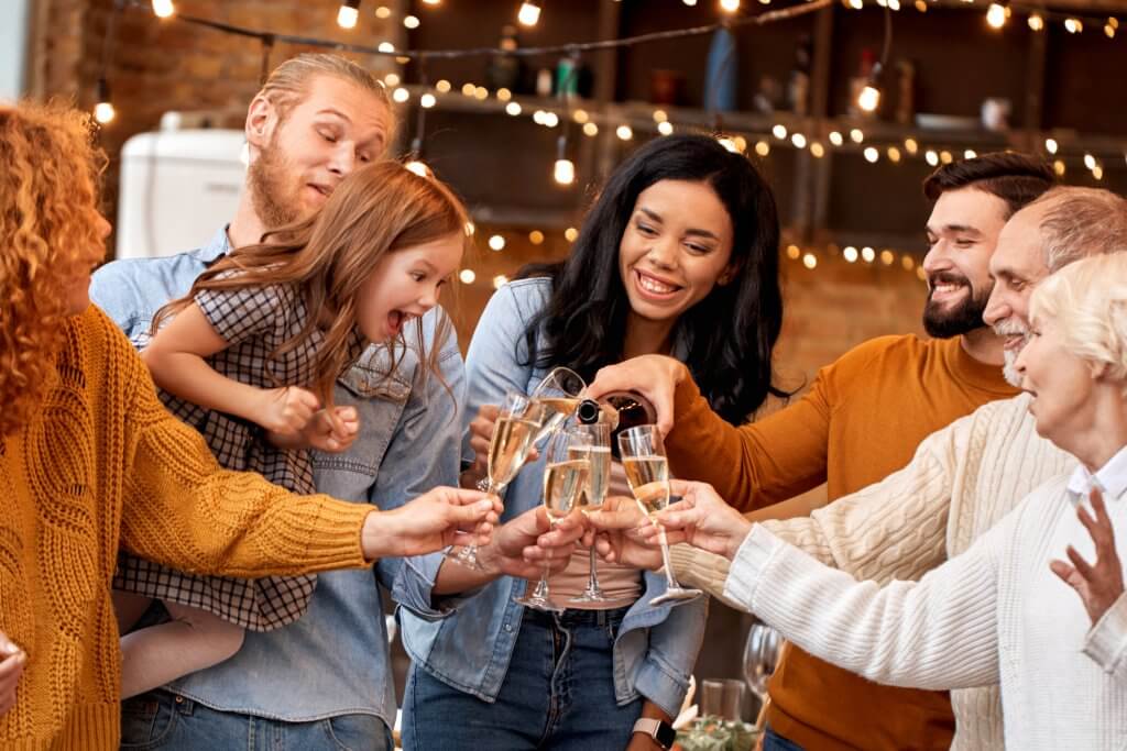 Happy multiracial family drinking champagne during holiday celebration in decorated flat. Christmas, New year, Thanksgiving, Anniversary, Hanukkah, Mothers day, Easter, engagement celebration